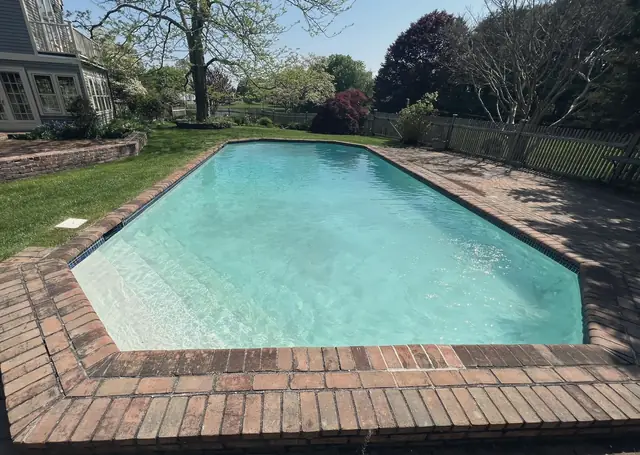 Pool with red brick coping set in a lawn among mature trees
